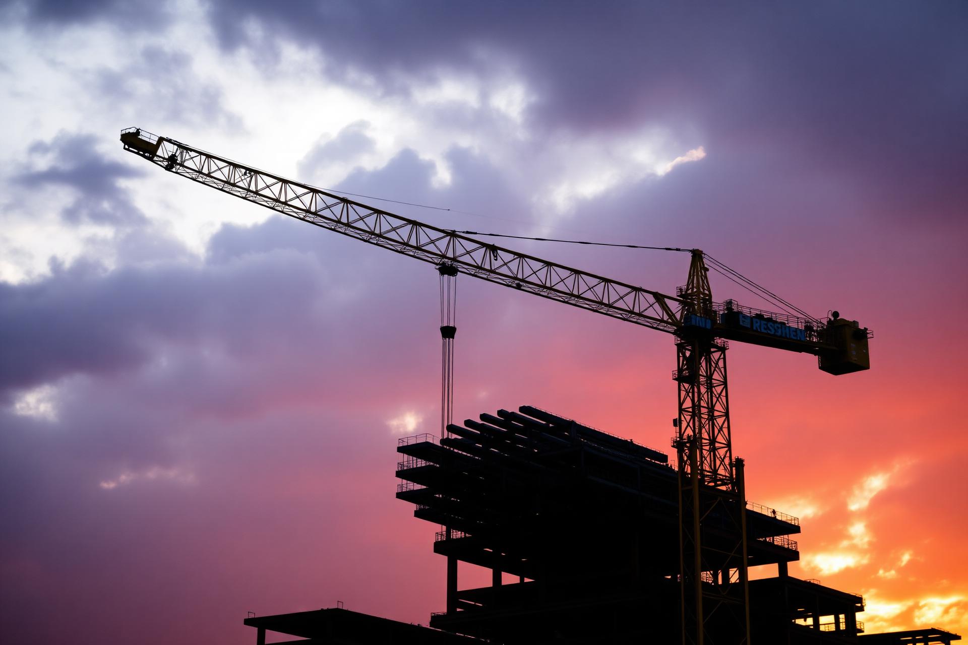 Crane lifting steel at dusk